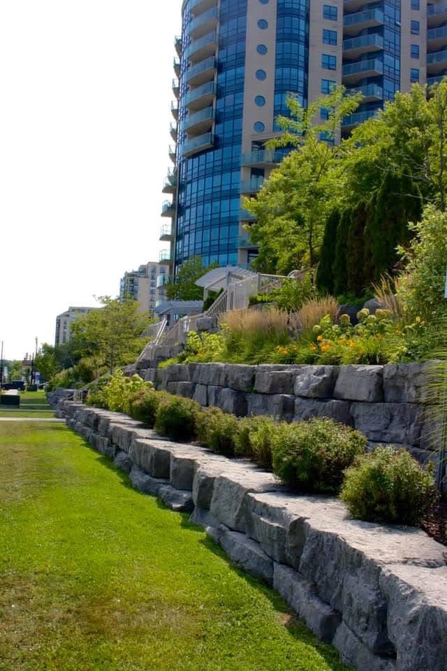 Multi-tiered granite retaining wall with hydrangeas at commercial high-rise